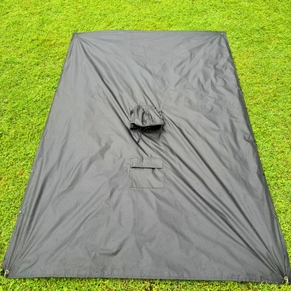The Trekshield rain poncho laid flat as a durable 2.1m x 1.4m groundsheet, demonstrating its use as a moisture barrier under sleeping bags or hiking gear in wet conditions.